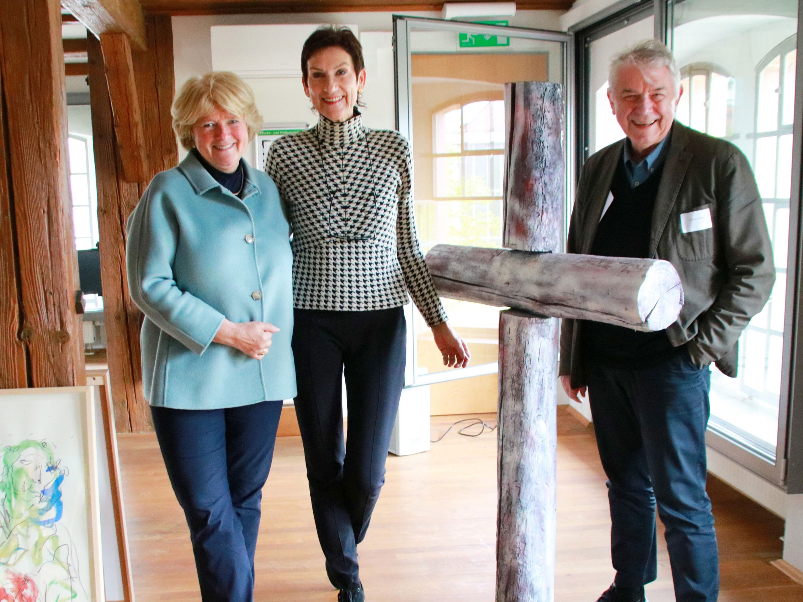 Von links nach rechts sind Prof. Monika Grütters, Christiane Theobald und Ulrich Khuon zu sehen. Sie stehen gruppiert um ein Holzkreuz des Künstlers Guillaume Bruère.