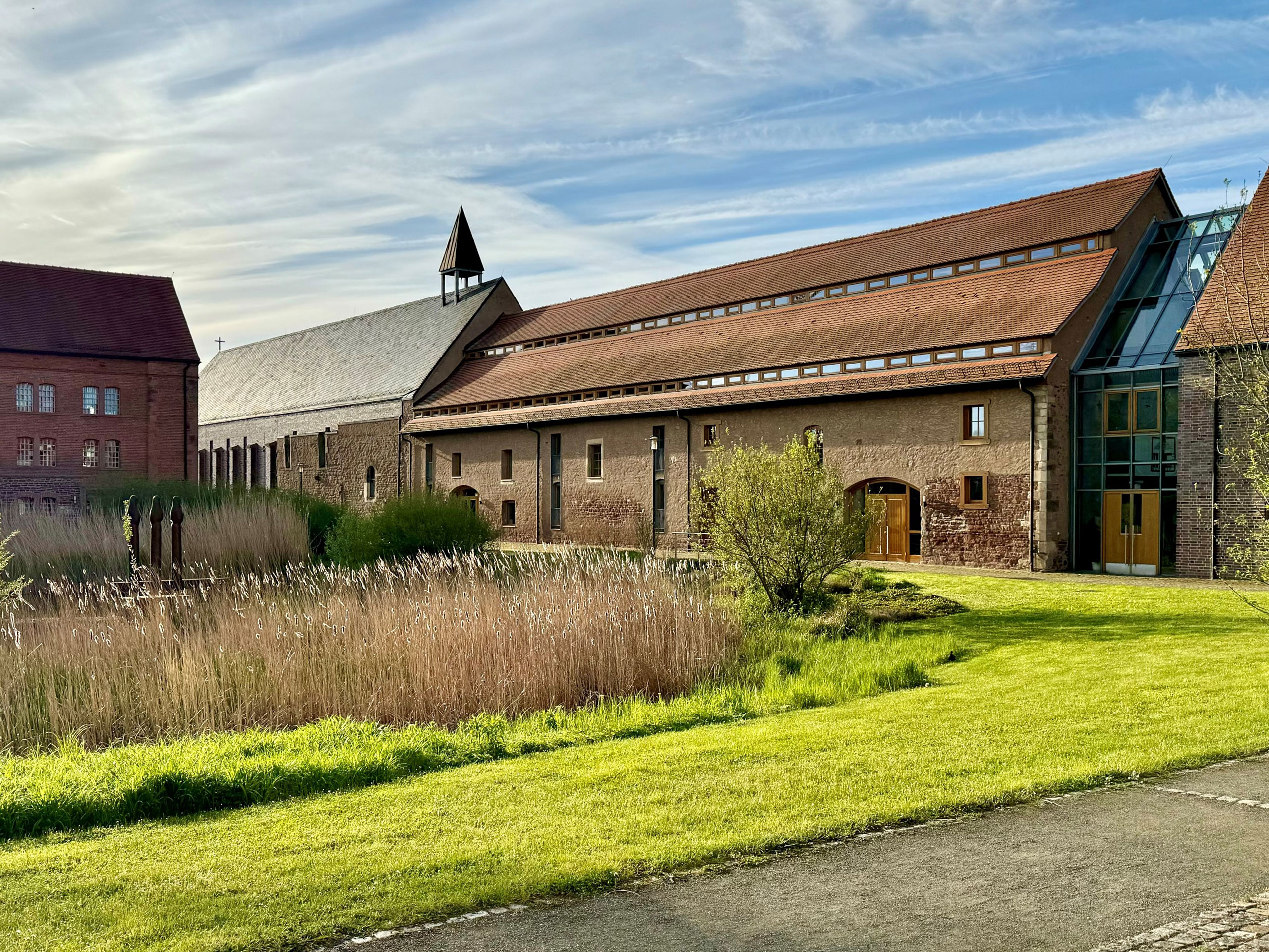 Kloster Helfta in Eisleben bei Sonnenschein und leichtbewölktem Himmel mit grünem Rasen davor
