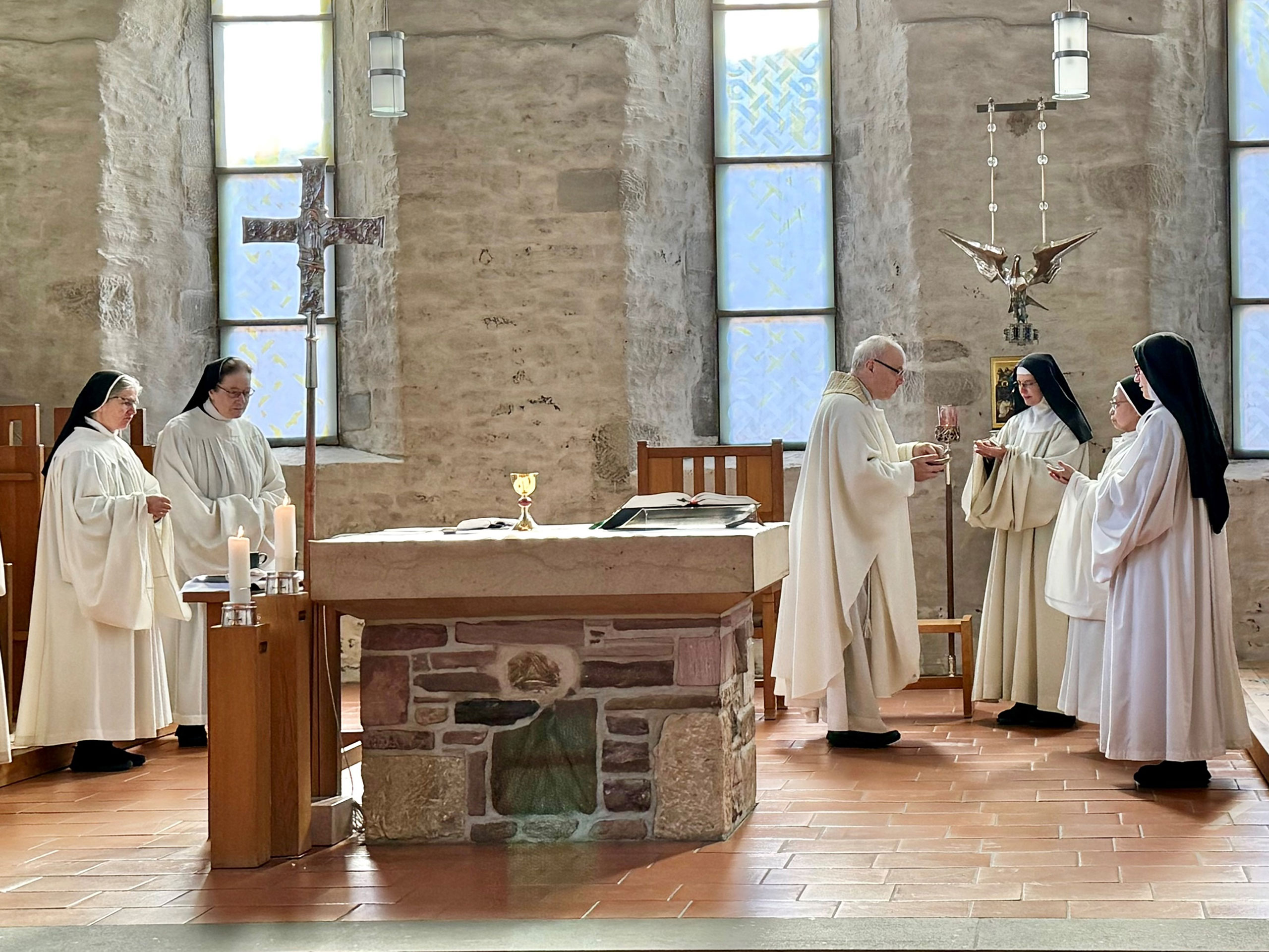 Pater Mertes im Altarraum bei der Messe mit vier Nonnen, die im Kreis um den Altar stehen